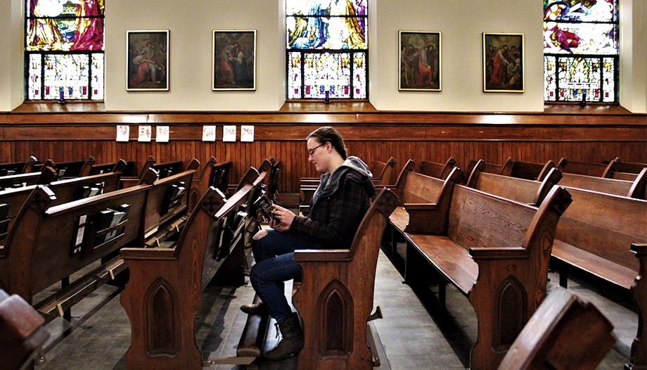 Chica joven leyendo un libro sentada dentro de una Iglesia.