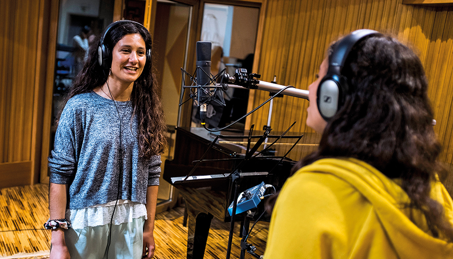 Chica joven cantando en un estudio de grabación.