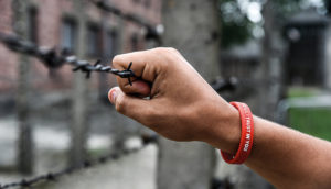 Mano de un niño tocando la alambrada del campo de concentración de Auschwitz.