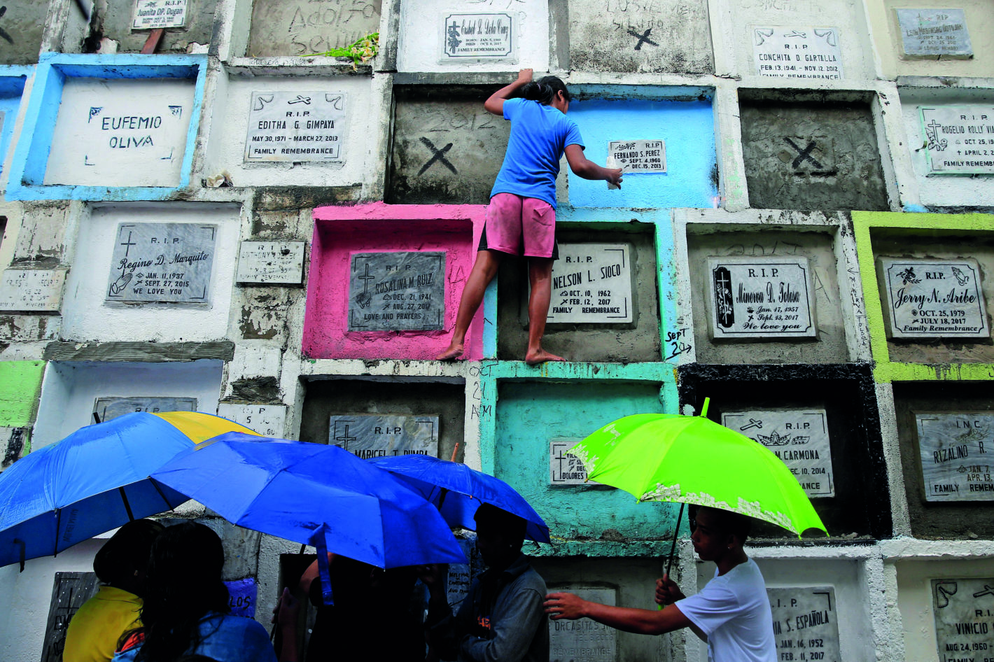 Gente llevando velas y flores en un cementerio en Manila, Filipinas.