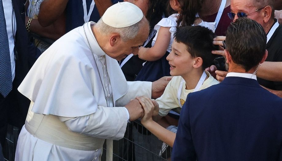 Papa saluda a un chico en Pavía, Italia.